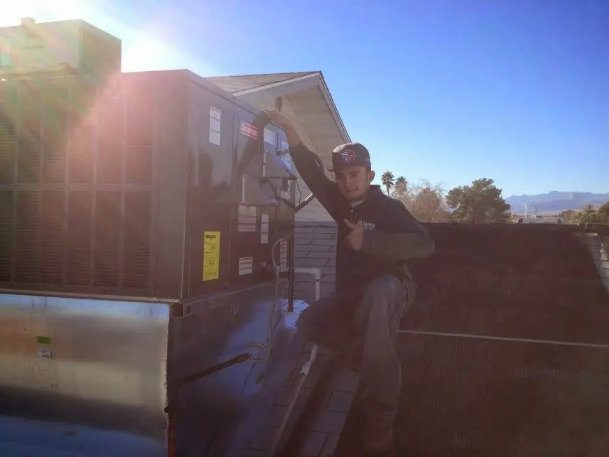 HVAC technician performing Boiler Repair on a rooftop unit in Kirtland